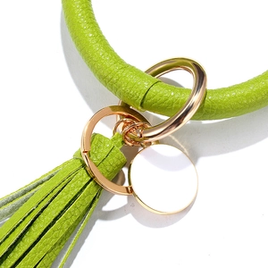 Detail of green leather keychain bracelet with tassel and gold polished metal ring