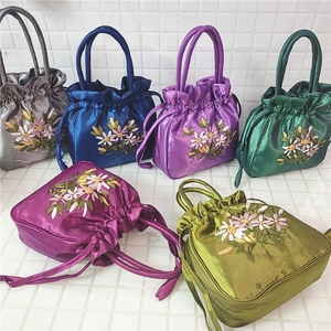 Detail of colorful satin drawstring handbags featuring delicate silk ribbon embroidery