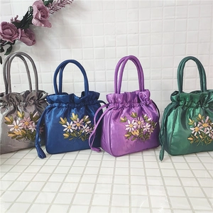 Detail of four satin drawstring bags with colorful 3D floral ribbon embroidery