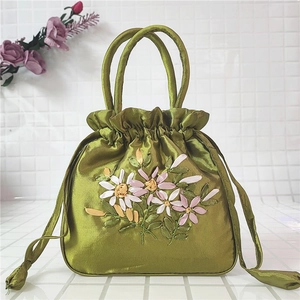 Detail of green satin handbag featuring floral ribbon embroidery and drawstring closure