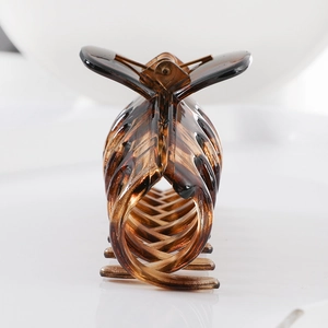 Macro shot of large amber tortoise shell claw clip with glossy plastic texture and spring