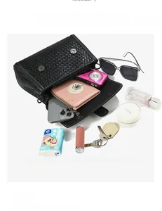 Detail showing high-capacity black woven handbag interior with phone and essentials