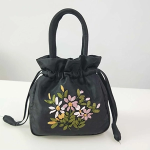Detail of floral embroidery on black satin drawstring bucket bag with single handle