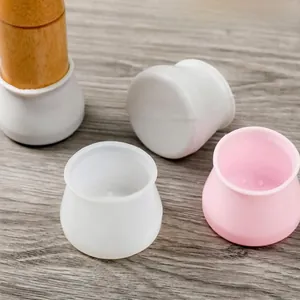 Detail of pink and white silicone chair leg protectors on wooden furniture legs