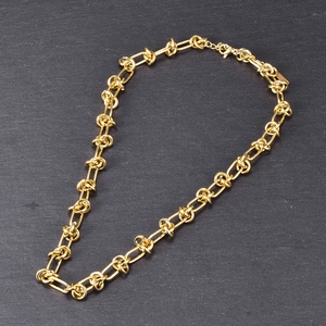 Detail of 18K gold chunky chain link necklace with lobster clasp on a stone surface
