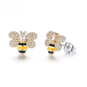 Detailed close-up of golden bee stud earrings with white rhinestones and striped enamel