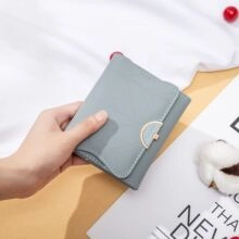 Close-up of grey-blue leather wallet featuring contrast stitching and gold metal buckle