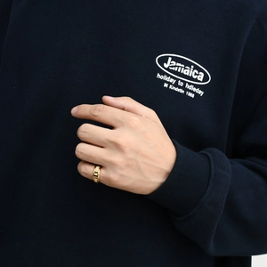 Detailed close-up of a men's gold ring with wood inlay on a hand over a navy hoodie