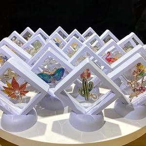 Floating PE film jewelry display boxes for enamel pins and brooches on rotating stand
