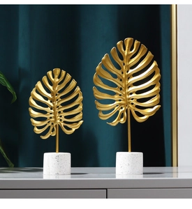 Detail of gold metal monstera leaves on a white terrazzo base for home decor