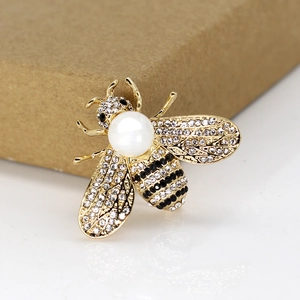 Macro shot of bee brooch featuring white pearls and black rhinestones on gold alloy