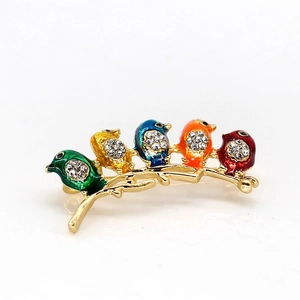 Detailed close-up of a golden branch brooch with five colorful enamel birds and rhinestones