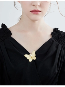 Detail of butterfly pearl brooch with shell texture wings on black garment fabric