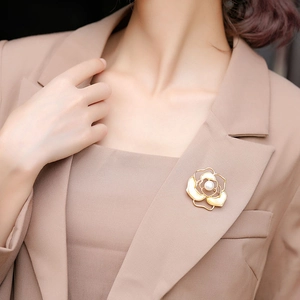 Detailed view of camellia brooch with pearl center worn on a beige blazer lapel