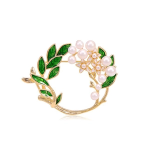 Detailed view of luxury wreath brooch with green leaves, white pearls and gold metal