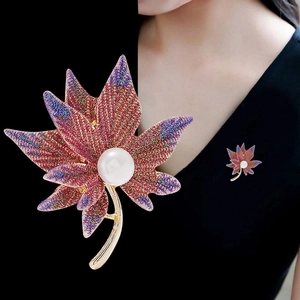 Detailed close-up of a maple leaf brooch with colorful glitter and a central pearl
