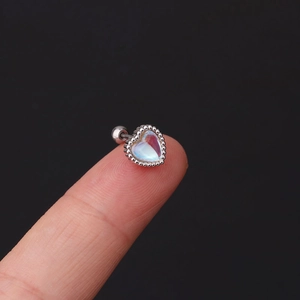 Macro shot of silver heart screw-back earring with iridescent stone and beaded edge