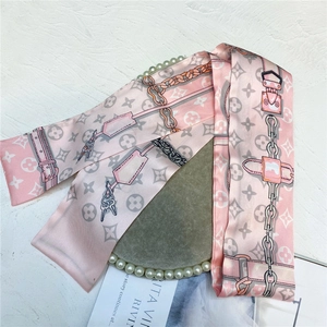Detail of pink satin scarf with grey monogram clover patterns and chain print