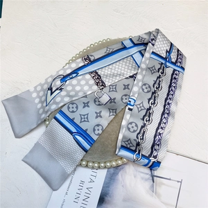 Detailed close-up of a satin-finish silk scarf with chains and floral patterns
