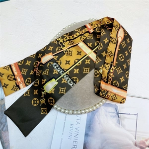 Detailed macro view of the vintage brown satin hair ribbon with clover motifs and golden chains