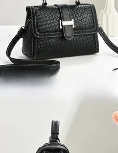 Detail view of black woven texture leather bag featuring silver metal lock and adjustable strap