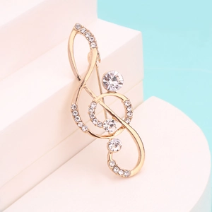 Macro detail of a gold-plated treble clef brooch with sparkling rhinestones on blue background