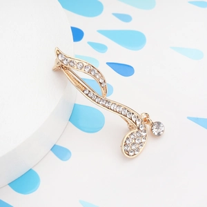 Macro shot of musical note brooch with sparkling rhinestones and a hanging crystal pendant
