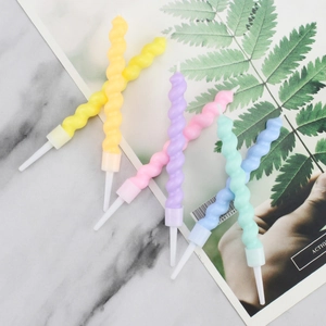 Set of six colorful macaron spiral birthday candles with holders on marble surface
