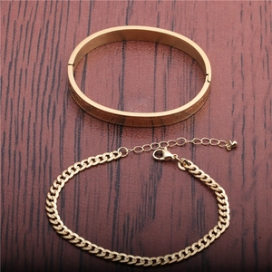 Gold Roman numeral cuff and flat Cuban chain bracelet set on a wooden surface