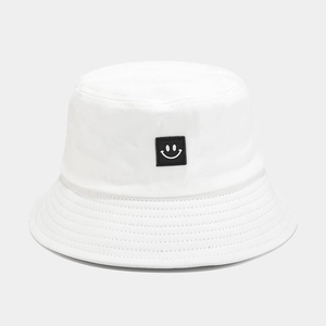 Detailed view of white cotton bucket hat with smile patch and reinforced stitched brim