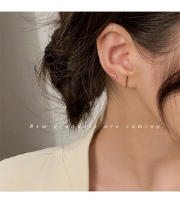 Close-up of minimalist gold geometric stud earrings set worn on ear for women