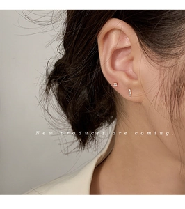 Close-up of minimalist gold stud earrings set with sparkling cubic zirconia on ear