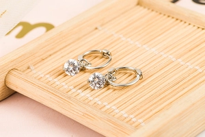 Close-up of S925 silver hoop earrings with a hanging round brilliant-cut zircon stone