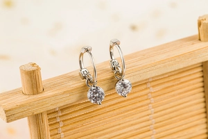 Macro shot of silver drop earrings with round-cut sparkling stones on a bamboo display