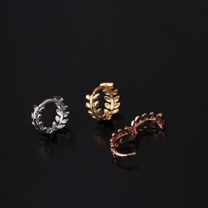 Three leaf-shaped metallic ear cuffs in silver, gold, and rose gold on black background