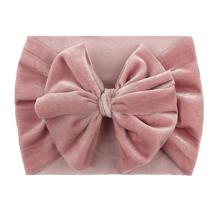 Close-up of pink velvet texture on a baby headband with a large stylish bow detail
