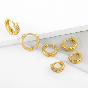 Macro shot of three sizes of gold huggie earrings with double-row zircon pavé and polished finish