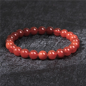 Close-up of 8mm red agate natural stone beads on a textured black background