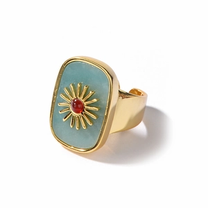 Detail of vintage gold-plated open ring with light blue stone and red center gem decoration