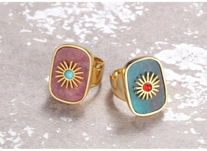 Detail of vintage gold flower rings with pink and turquoise natural stones on gray stone