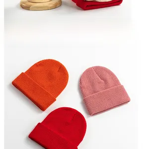 Detailed close-up of thick ribbed knit beanies in vibrant orange, pink and red tones