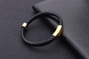 Détail du bracelet en cuir tressé noir avec fermoir magnétique doré sur portefeuille