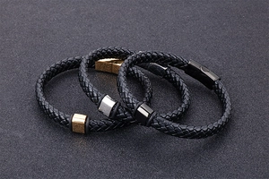 Gros plan de bracelets en cuir tressé avec fermoirs en acier inoxydable or, argent et noir