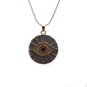 Close-up of golden evil eye pendant with blue and clear zircon crystals on thin chain