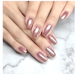 Close-up of rose gold mirror chrome nail powder effect on hands over marble background