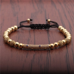 Macro detail of gold beads and micro-paved evil eye charm on adjustable woven bracelet
