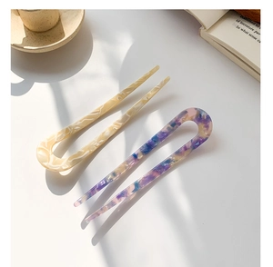 Detailed view of U-shaped acetate hair pins with marble patterns on a minimalist background