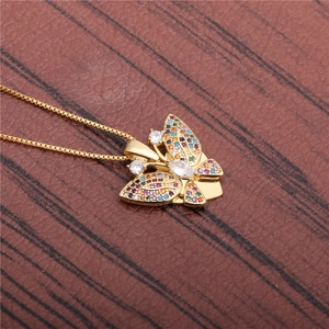 Exquisite goldene Schmetterling-Halskette mit bunten Zirkonsteinen auf dunklem Holzgrund