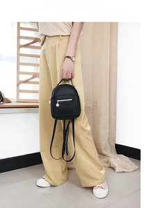 Detail showing a stylish small black PU leather backpack with gold zippers and charms