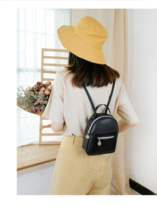 Detailed view of black PU leather backpack with silver zippers and round hardware accents